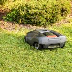 Ein M&auml;hroboter f&auml;hrt &uuml;ber eine Wiese. Das Ger&auml;t f&auml;hrt auf eine Hecke zu.