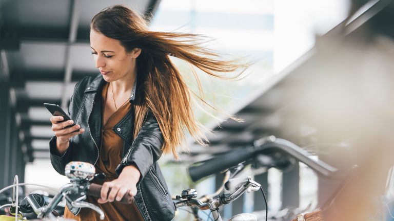 Eine Person mit einem Fahrrad schaut auf ihr Smartphone.