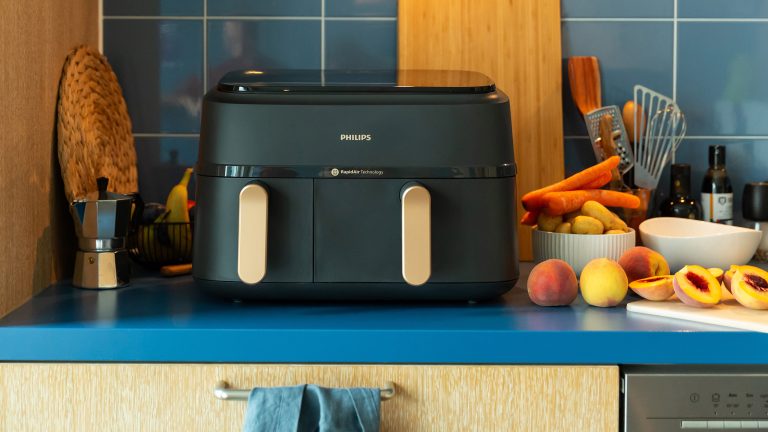 Ein Philips Series 3000 Dual Basket Airfryer steht auf einer K&uuml;chenzeile. Daneben und dahinter verschiedene K&uuml;chenutensilien.