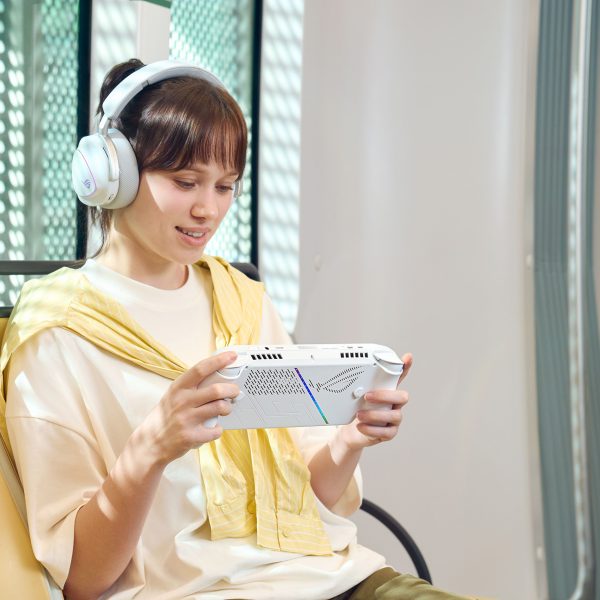 Eine Person hält ein ROG Ally in der Hand und spielt darauf etwas in einer Bahn.