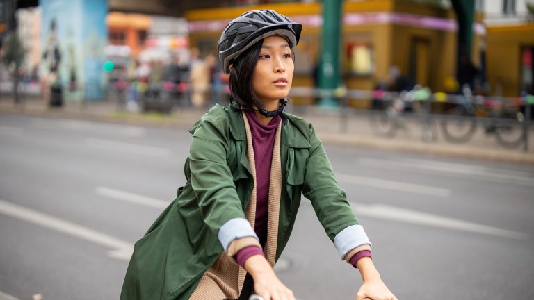 Eine Person auf einem Fahrrad in der Stadt tr&auml;gt einen Helm.