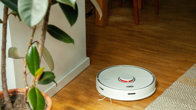 Ein Saugroboter fährt über einen Holzboden.