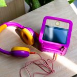 Eine lilafarbene Tigerbox und lila-gelbe Tigerbuddies sind von oben zu sehen. Sie stehen auf einem holzfarbenen Tisch.