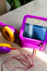 Urlaub mit Kindern, 12 Gadgets für die Kleinen Eine lilafarbene Tigerbox und lila-gelbe Tigerbuddies sind von oben zu sehen. Sie stehen auf einem holzfarbenen Tisch.