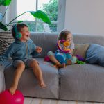 Zwei Kinder auf einem Sofa h&ouml;ren zusammen an einer Tigerbox MINI mit den Kopfh&ouml;rern Tigerbuddies etwas.