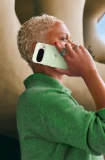 Eine Person steht vor einem futuristischen Geb&auml;ude und h&auml;lt ein mintgr&uuml;nes Google Pixel 10 Pro an ihr Ohr.