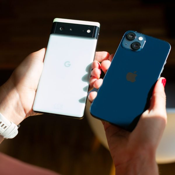 Eine Person hält ein Google Pixel und ein iPhone nebeneinander.