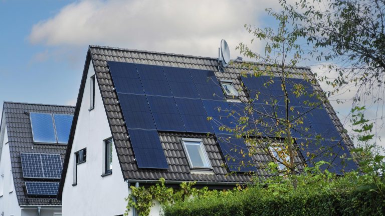 Aufnahme eines Einfamilienhauses mit Spitzdach auf dem eine Solaranlage installiert ist.
