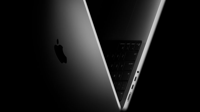 Ein Seitenanblick eines halb aufgeklappten und nur teilweise beleuchteten MacBook Pros.