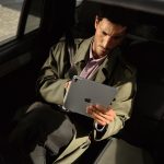 Eine Person sitzt auf der Rückbank eines Autos und hält ein iPad Pro vor sich in der Hand.