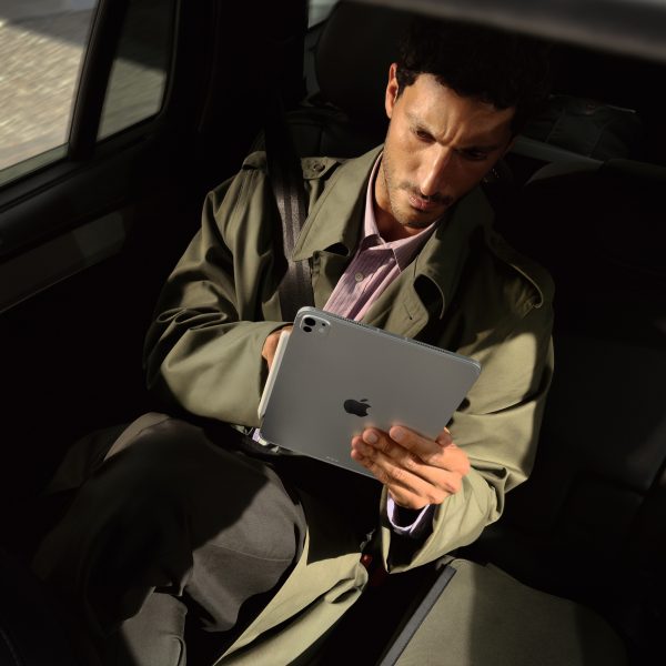 Eine Person sitzt auf der R&uuml;ckbank eines Autos und h&auml;lt ein iPad Pro vor sich in der Hand.