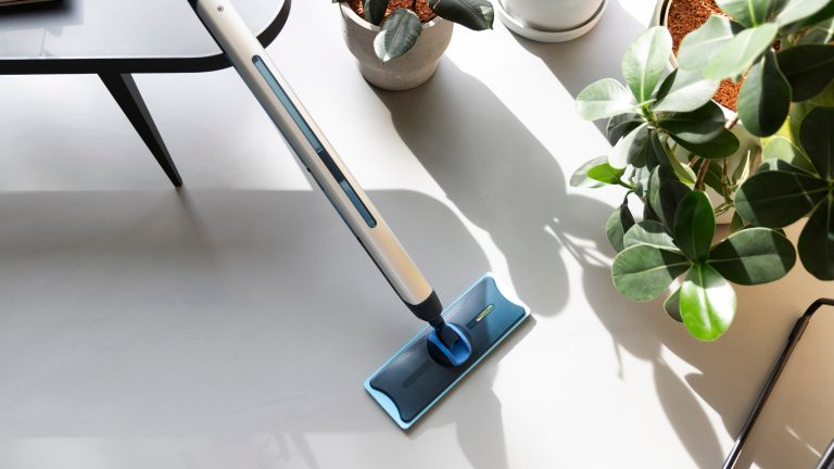 Der Philips OneUp steht auf dem Boden und lehnt dabei an einem Tisch.