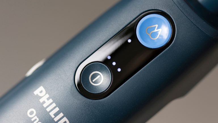 Philips-OneUp-12 Detailsaufnahme des Griffs des Philips OneUP mit dem Knopf zum Ein-und Ausschalten und dem Knopf zur Regulierung der Feuchtiggkeitsstufe. Es leuchtet eine LED unterhalb des Knopfes zur Feuchtigkeitsregulierung und drei LEDs oberhalb des Startknopfs.