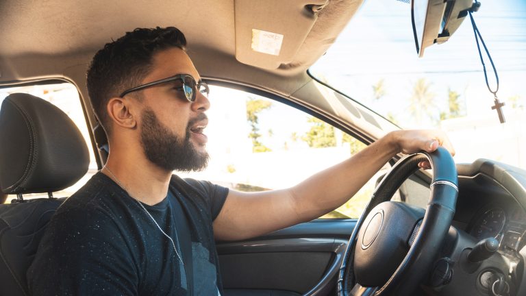 Eine Person sitzt im Auto und fährt, während sie eine Nachricht diktiert.