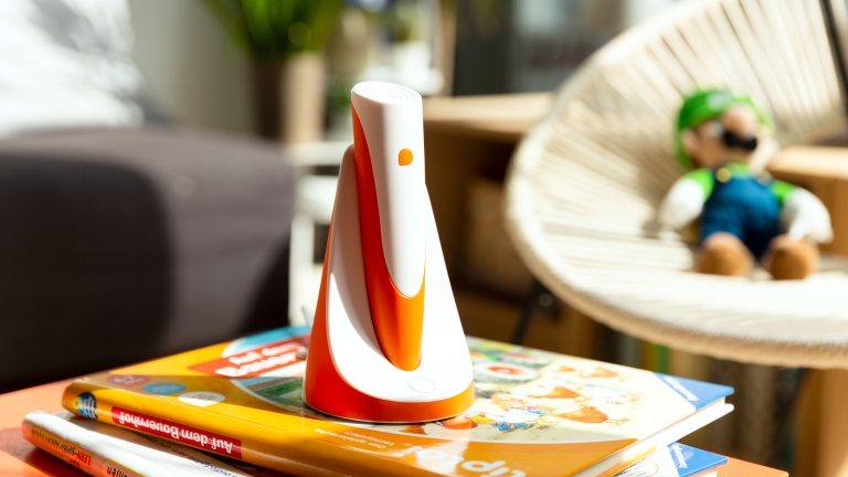 Weihnachtsgeschenke für Kinder, Technik zum Spielen und Lernen Ein Tiptoi-Stift in Orange und Weiß steht auf einem Stapel Kinderbücher.