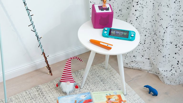 Eine Toniebox, eine Nintendo Switch Lite und ein Tiptoi-Stift auf einem kleinen Tisch.