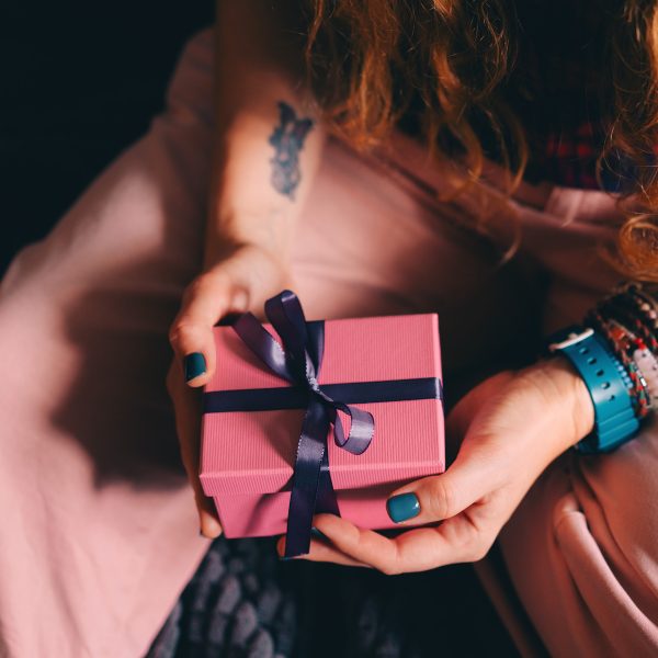 Vogelperspektive auf eine Person, die ein kleines Geschenk in beiden H&auml;nden h&auml;lt.