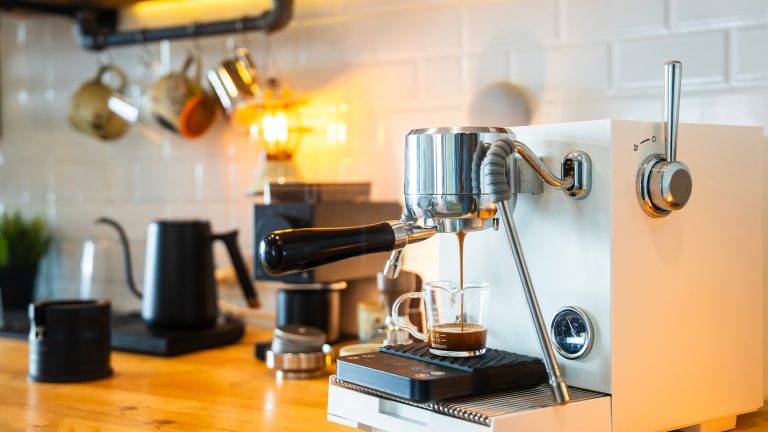 Eine Siebtr&auml;germaschine steht auf einer K&uuml;chenzeile. Gerade l&auml;uft ein Espresso in eine Glastasse.