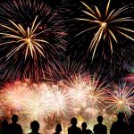 Die dunklen Silhouetten von mehreren Menschen vor einem n&auml;chtlichen Feuerwerk.
