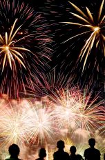 Die dunklen Silhouetten von mehreren Menschen vor einem n&auml;chtlichen Feuerwerk.