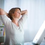 Eine Tageslichtlampe strahlt eine Person von einem Tisch aus an.