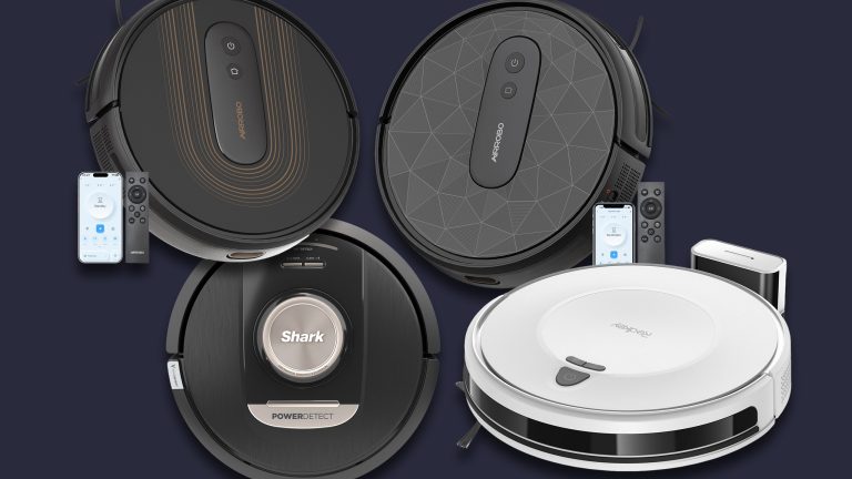 Vier verschiedene Saugroboter und ein paar Fernbedienungen freigestellt vor dunklem Hintergrund.