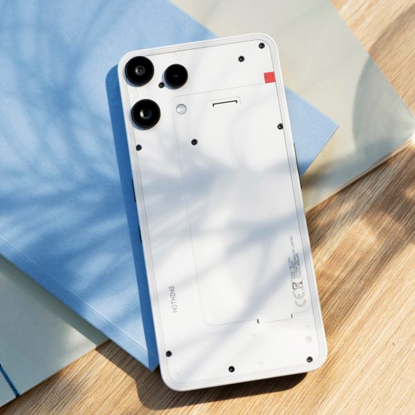 Bild von einem Nothing Phone (3a) Lite, das auf einem Notizbuch auf einem Tisch liegt.
