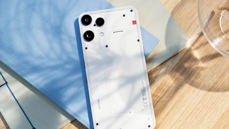 Bild von einem Nothing Phone (3a) Lite, das auf einem Notizbuch auf einem Tisch liegt.