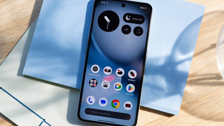 Smartphones unter 300 Euro, 5 günstige Handys Blick auf ein Nothing Phone (3a) Lite, das auf einem Notizbuch liegt. Zu sehen ist die Front, das Display ist eingeschaltet.