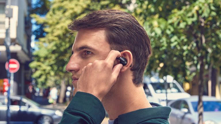 Eine Person in einer Stadt tr&auml;gt einen Open-Ear-Kopfh&ouml;rer.