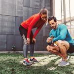 Zwei Personen sind in Sportkleidung auf einem Hinterhof und schauen zusammen auf ein Smartphone.