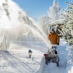Eine Person in dicken Winterklamotten r&auml;umt im tiefen Schnee einen kleinen Weg frei.