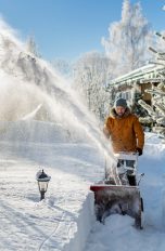 Eine Person in dicken Winterklamotten r&auml;umt im tiefen Schnee einen kleinen Weg frei.
