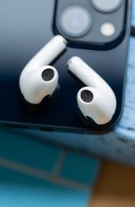 Zwei AirPods liegen auf der R&uuml;ckseite eines iPhones.
