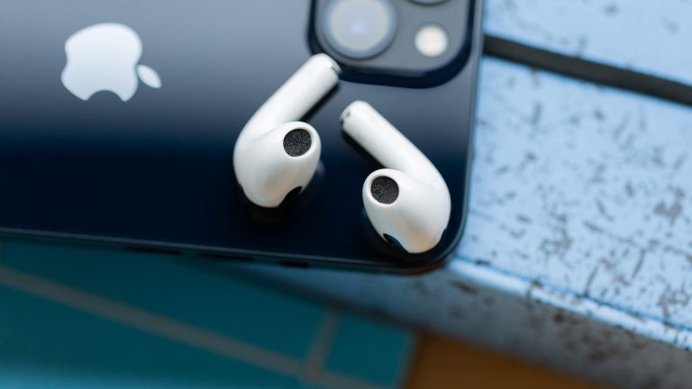 Zwei AirPods liegen auf der R&uuml;ckseite eines iPhones.