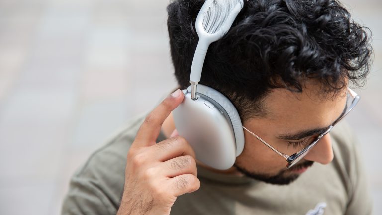 AirPods, Die aktuellen Modelle in der Übersicht Eine Person trägt die AirPods Max in Silber und bedient die Steuerung an der Seite.