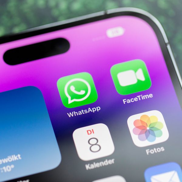 Der obere Teil eines iPhones, das auf einem Tisch liegt. Darauf sind verschiedene Apps, unter anderem WhatsApp zu sehen.