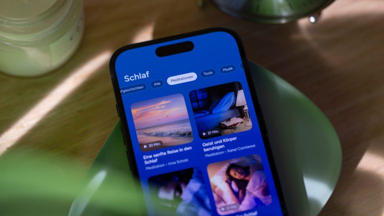 Auf einem iPhone, das auf einer gr&uuml;nen, flachen Schale liegt, ist eine Schlaf-App ge&ouml;ffnet.