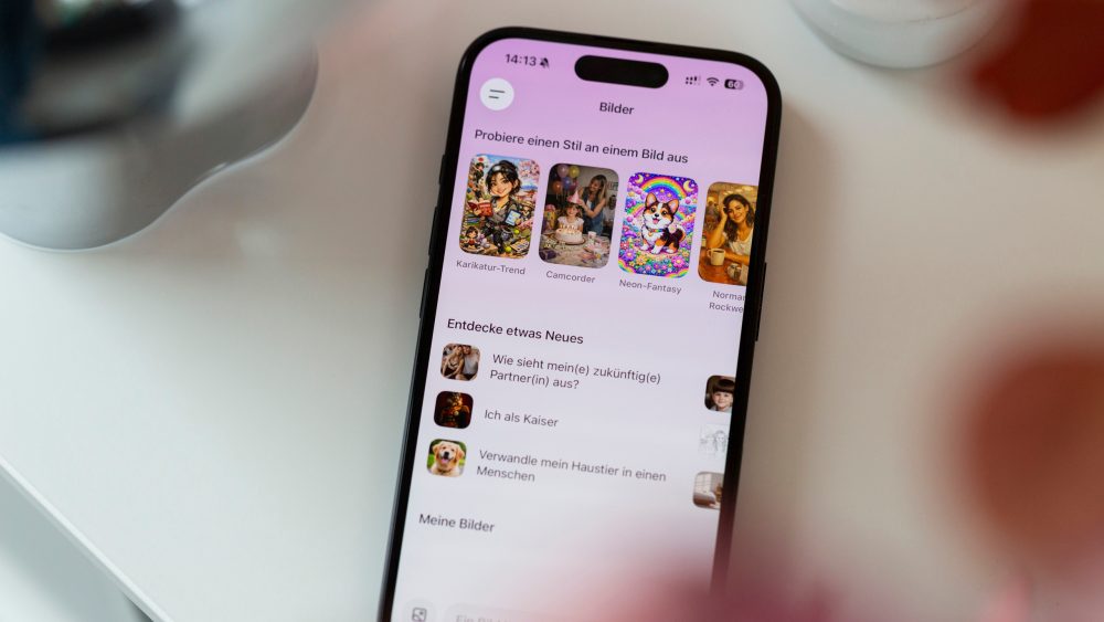 Ein iPhone liegt auf einer wei&szlig;en Oberfl&auml;che. Der Bildschirm ist entsperrt und ein KI-Bildgenerator ist ge&ouml;ffnet.