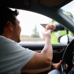 Eine Person ist in eine Fahrzeugkontrolle geraten und reicht der Polizei die Fahrzeugpapiere durchs Fenster.
