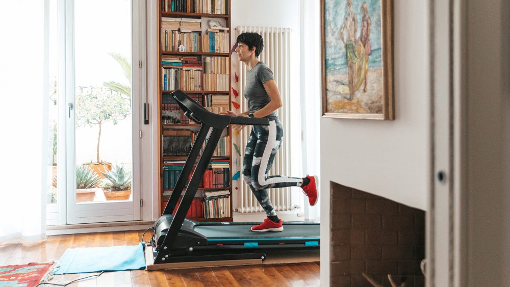 Eine Person trainiert auf einem Laufband in Sportkleidung in ihrem Flur.