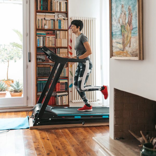 Eine Person trainiert auf einem Laufband in Sportkleidung in ihrem Flur.