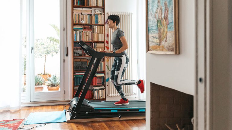 Eine Person trainiert auf einem Laufband in Sportkleidung in ihrem Flur.
