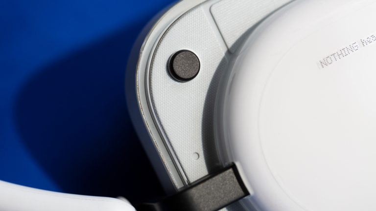 Der Schnellwahlbutton an der Au&szlig;enseite einer Ohrmuschel der Headphone (a).