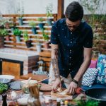 Eine Person steht drau&szlig;en vor einer reich bef&uuml;llten Arbeitsplatte und bereitet Essen vor.