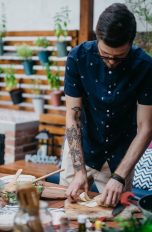 Outdoor-Küche einrichten, Das brauchst du an Geräten, Technik und Ausstattung Eine Person steht draußen vor einer reich befüllten Arbeitsplatte und bereitet Essen vor.