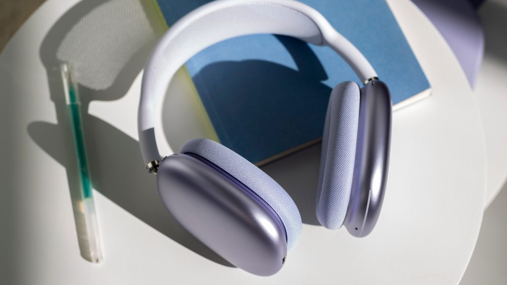 (Die AirPods Max 2 in der Farbe Violett liegen auf einem Notizbuch, daneben liegt ein Stift.)