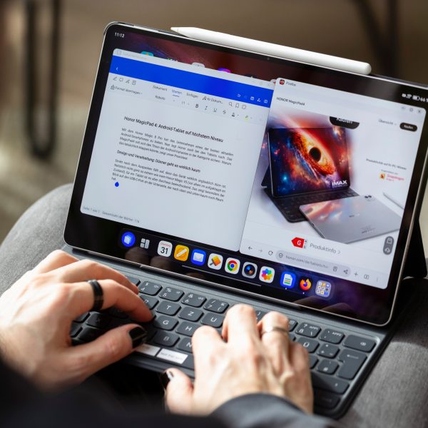 Eine Person tippt auf der Tastatur eines Honor MagicPad 4, auf dessen Bildschirm ein Textdokument ge&ouml;ffnet ist.