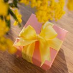 Bild von einem kleinen Geschenk, das unterhalb eines Blumenstrau&szlig;es liegt.