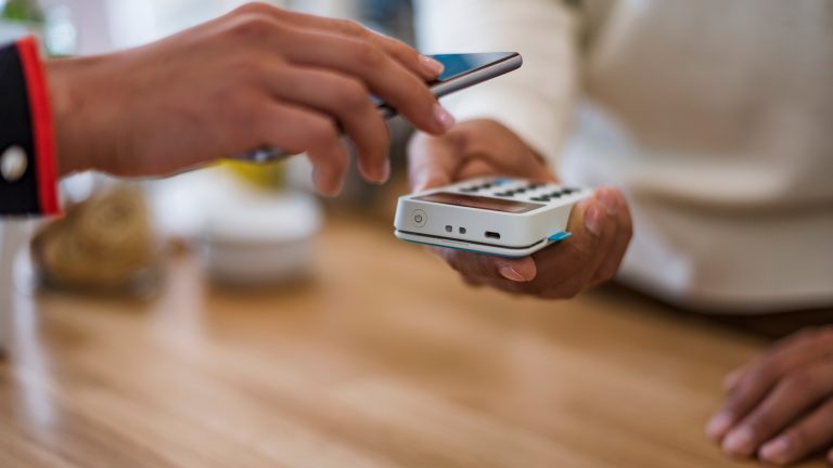 Eine Person bezahlt mit ihrem Smartphone per NFC.